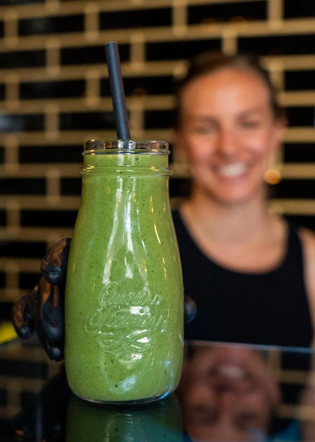 Teammember gëtt e grénge Smoothie iwwer d’Theek